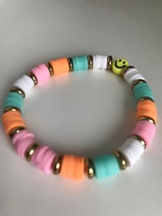 This bracelet is called Sunset smiles. It is made with clay beads, flat gold beads, and a smiley face bead and the colors are pink, orange, white, teal, and yellow. This bracelet is 6.5 inches. If you want a bigger or small size message me. Fun Multicolor Stretch Bracelet For Everyday, Cheerful Multicolor Everyday Bracelets, Cheerful White Bracelets With Colorful Beads, Multicolor Smiley Face Bracelets For Everyday Wear, Beach Jewelry With Smiley Face Round Beads, Multicolor Smiley Face Bracelets For Everyday, Everyday Pink Smiley Face Bracelets, Fun Smiley Face Round Bead Bracelets, Multicolor Smiley Face Jewelry For Everyday