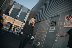 a woman standing next to a wall with graffiti on it and another person pointing at her