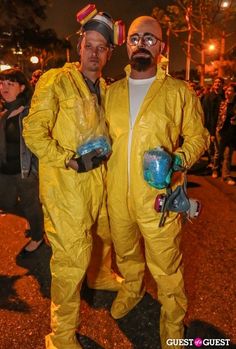 two men in yellow suits standing next to each other on the street at night time