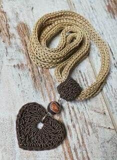 a brown heart shaped pendant on a rope necklace with an orange stone bead in the center