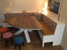 a wooden table sitting under a window next to two stools and a painting on the wall