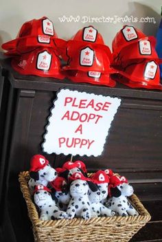 a basket filled with stuffed animals sitting on top of a wooden table next to a sign that says please adopt a puppy