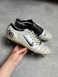 a person holding two soccer shoes in their hand