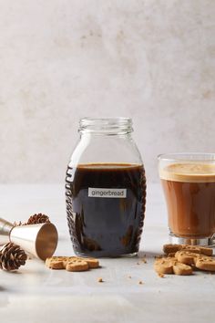 a glass jar filled with liquid next to cookies and a shaker on a table