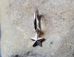 a silver star charm sitting on top of a gray rock next to a pair of scissors