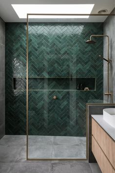 a bathroom with green tiles on the walls and floor, along with a walk in shower