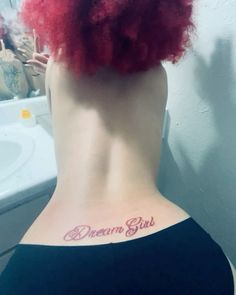 a woman with red hair has a tattoo on her back