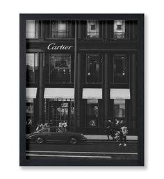 a black and white photo of a car parked in front of a cartier store