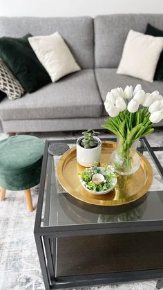 a living room filled with furniture and flowers on top of a glass topped coffee table