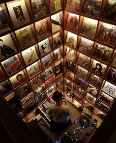 a man sitting at a desk in front of a wall full of records