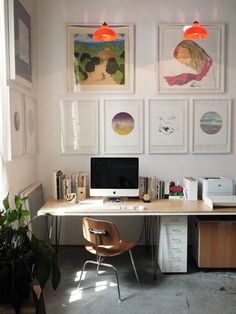 a desk with a computer on top of it next to a potted plant and pictures