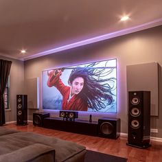 a living room with a large screen tv and speakers