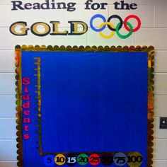 a bulletin board with the olympic symbol on it in front of a wall that reads reading for the gold