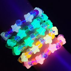 several different colored bracelets on a black background with light shining through the top and bottom