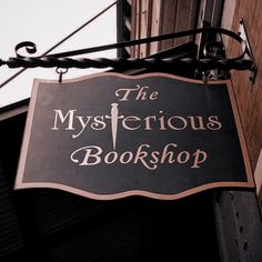 the mysterious bookshop sign is hanging from the side of a building