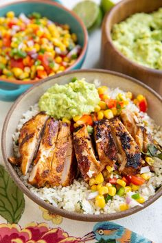 two bowls filled with rice and chicken next to guacamole, avocado and corn