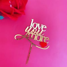 a cake topper that says love you more with a heart on it next to a rose