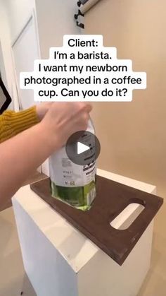 a person is holding a bottle of liquid in front of a coffee cup on top of a counter