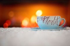 a coffee cup with the words enough chocolate on it sitting on a saucer in front of a fireplace