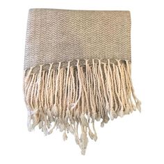 a white and beige blanket with fringes on it's end, against a white background