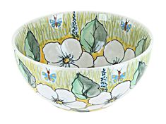 a bowl with white flowers and green leaves on the inside, sitting in front of a white background