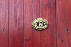 a wooden door with a brass plaque on it's side and the number thirteen