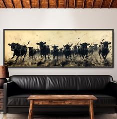 a living room with a couch, table and cow painting on the wall above it