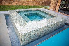 an outdoor swimming pool in the middle of a yard with grass and brick wall behind it