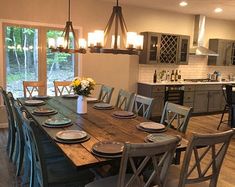 a dining room table with chairs and plates on it in front of an open kitchen