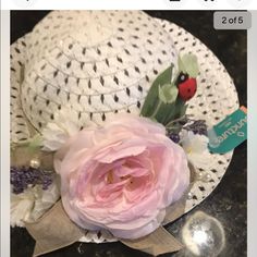 a white hat with pink flowers and a ladybug on the side, sitting on a table