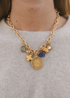 Elevate your style with our 16" gold-filled chain vintage-inspired charm necklace. This exquisite piece features seven unique charms: St. Benedict coin, gold cross, mini heart with rhinestones, love pendant, bezeled rhinestone charm, vintage spiral shell, and a playful blue fun heart. A perfect blend of elegance and ch Coin Charm Necklace, Gold Pendant Charm Necklace, Charm Necklace Outfit, Diy Charm Necklace Ideas, Vintage Charm Necklace, Chunky Charm Necklace, Charm Necklace Aesthetic, Charm Necklace Ideas, Logan Tay