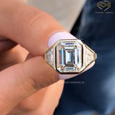 a close up of a person holding a ring with an emerald and diamond in it