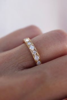 a woman's hand with a yellow gold wedding band and diamond ring on it