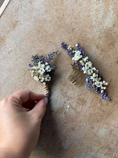 two combs with flowers on them are being held by a person's hand