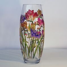 a glass vase with flowers painted on it