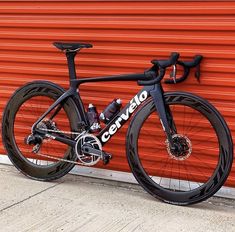 a black and white bike leaning against a red wall with the words cannon written on it