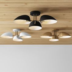 an overhead view of several lights on a wooden ceiling with white and black shades hanging from the ceiling