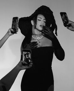 a black and white photo of a woman with her hands on her hips, while three other people hold their cell phones