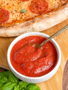 a pizza sitting on top of a wooden cutting board next to a bowl of sauce