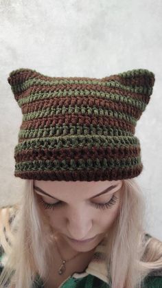 a woman wearing a green and brown knitted cat hat with ears on her head