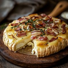 a close up of a pizza on a wooden plate with cheese and bacon toppings