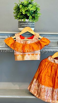 This Orange Venkatagiri Silk Skirt And Top exudes elegance with its zari borders and off shoulder style top. The perfect combination of tradition and modernity, its bright color adds a touch of beauty. Crafted from premium silk, it offers both comfort and sophistication to your little one. Kids Wear Boys, Pleated Saree, Fancy Clutch, Kids Wear Girls, Block Print Saree, Silk Saree Banarasi, Silk Thread Bangles, Fancy Gowns, Bridal Silk Saree