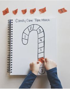 a child's hands holding up a candy cane tape match book with numbers on it