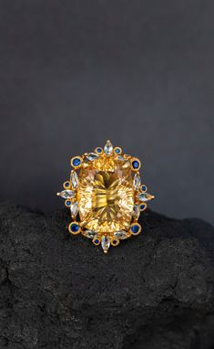 Statement ring with a huge natural yellow citrine framed in intricate lace of blue sapphire and topaz ! It's so stunning on a hand, you will fall in love with it :) ♥ The ring in the video is in size 6 US, the model has rather small hands :) ♥ The design can be made with gemstones of your choosing ♥ Each order will be gift wrapped beautifully ♥ QUALITY: Each item is stamped according to US regulations.  ------   *DIMENSIONS*  ------ ♥ Ring Size: All sizes will be made to order Main Metal: 925 St Luxury Crystal Ring With Gemstone Accents For Wedding, Elegant Citrine Crystal Ring With Gemstone, Exquisite Topaz Ring With Gemstone Accents As Gift, Elegant Citrine Crystal Ring, Elegant Yellow Sapphire Gemstone Jewelry, Luxury Yellow Sapphire Ring, Luxury Citrine Topaz Ring With Gemstone Accents, Gold Topaz Ring With Gemstone Accents, Elegant Citrine Ring Jewelry