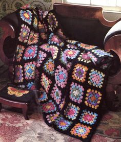 a crocheted granny blanket sitting on top of a chair next to a window