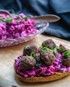 some meatballs and red cabbage on a wooden board