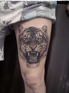 a man's leg with a tiger tattoo on it and his mouth is open