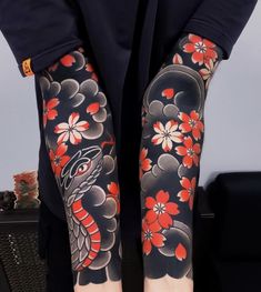 a woman with red flowers on her arm and leg sleeve, holding a black suitcase