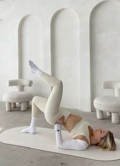 a woman is doing yoga on a mat in a room with white walls and chairs