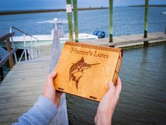 a person holding up a wooden box with a marlin on it that says hunter's lures